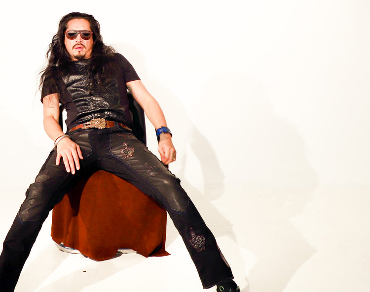 A stylish man wearing The Python Tee with black leather pants, sunglasses, and long hair, exuding confidence and elegance.